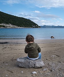 Gabriel at Prapratno Beach, sitting on a rock, Croatia