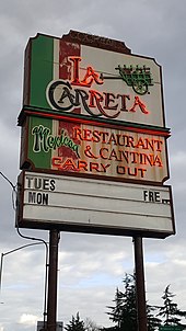 Фотография неоновой вывески с надписью "Мексиканский ресторан и кантина La Carreta" и "Carry Out".