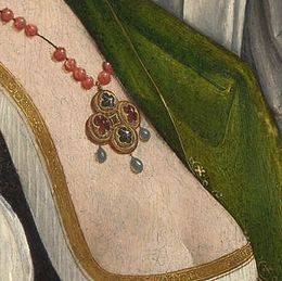 Crop showing the pendant of glass beads strung on cord culminating in point-cut diamonds and rubies. Although the work is ostentatiously pious, its sensual daring, seen here in the lace opening of the underdress, indicates the new freedom available to some well-patronised artists of the early 16th century Magdalen Weeping detail.jpg