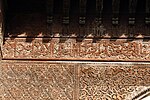 Inscripción caligráfica árabe tallada en madera en la madrasa Sahrij de Fez, de principios del siglo XIV, rodeada de otra decoración arabesca