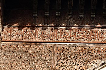 Calligraphic inscription carved into wood in the Sahrij Madrasa in Fes, surrounded by other arabesque decoration (early 14th century)