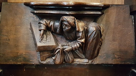 Detail of a misericord on a choir stall- a money-changer