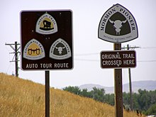 Road signs depicting logos for national historic trails, labeled "Auto tour route" and "Original trail crossed here"