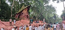 Tourists and worshippers scamper around the Osun groove Osun-worshipper 09.jpg