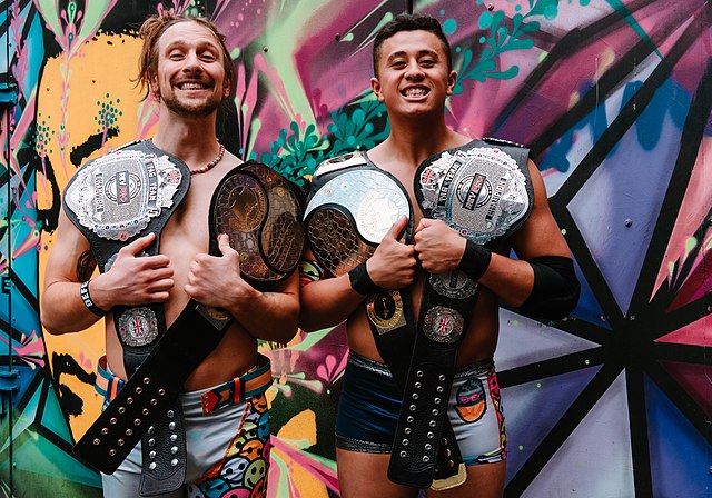 Sunshine Machine (Chuck Mambo and TK Cooper) with the titles on their left shoulder in 2022