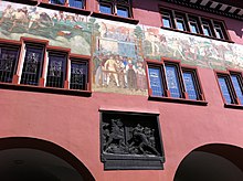 Bronze-Relief. Uli Rotach kämpft vor der brennenden Hütte gegen den Feind.