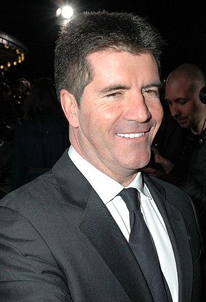 man in black suit with black tie and white shirt smiling toward camera