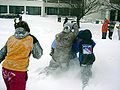 Cuatro estudiantes realizan un ataque coordinado durante una pelea de bolas de nieve.