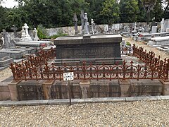 Fotografía de una tumba rodeada por una puerta en un cementerio.