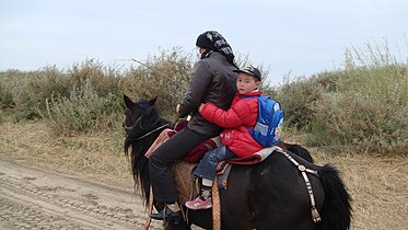 2010年9月12日哈薩克婦女騎馬送孩子上學
