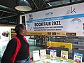 A lady in front of the large banner "Rwanda Children's Book Organization. Book Fair 2021".