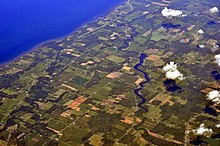 Aerial view of Oak Orchard Creek, 2013. The creek is slightly right of center in the photo, running roughly vertically from the bottom of the image to the lake at top. Aerial - NY Lake Ontario shore near Oak Orchard Marine Park 03 - white balanced (9645354673).jpg