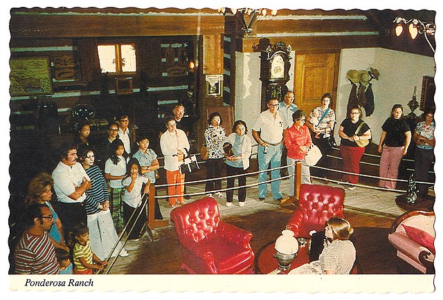 Ponderosa tour postcard – visitors tour the replica ranchhouse and its big living room with stone fireplace overlooking the east shore of Lake Tahoe, 