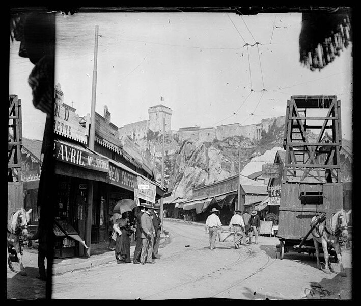 File:Carrer de Lorda amb botigues, alguna gent i un cavall, al fons el castell amb una torre.jpeg