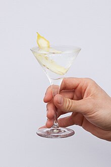 a clear beverage and lemon twist in a triangular glass