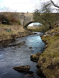 Uma ponte em arco de pedra sobre um beck