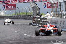 Fotografia colorida de um monoposto nas ruas de uma cidade.