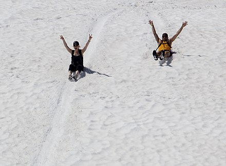Two people glissading while sitting