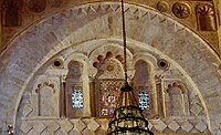 Photographie de la décoration du tympan de l’arc qui se trouve au-dessus du mihrab. Le tympan est occupé par cinq niches de différentes tailles, dont celle du milieu est la plus grande. La décoration de ce dernier inclut des carrés posés sur la pointe, des arcs à cinq lobes et des claustras à verres de couleur.