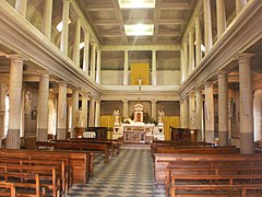 Salle rectangulaire sur deux niveaux ; au premier, deux rangées de colonnes ; l'autel est au fond, au centre ; au premier plan, des bans en bois posés sur un carrelage noir et blanc en damier.