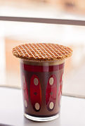 A stroopwafel is placed over a hot drink such as coffee or tea to warm the cookie and soften the syrup