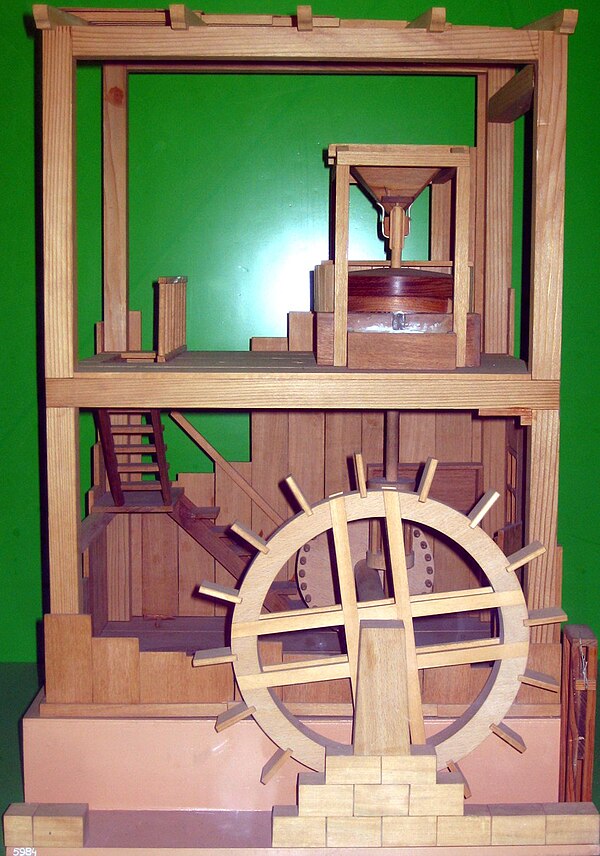 Model of a Roman water-powered grain mill described by Vitruvius. The millstone (upper floor) is powered by an undershot waterwheel by the way of a ge