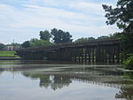 Een brede rivier stroomt onder een snelwegbrug.