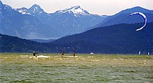 A kitesurfer passes two skimboarders during an early season low tide on the Spanish Banks. Mountains in the background are on the west side of Howe Sound. Spanish Banks Sports.jpg