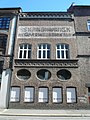 Malt skilt: Skandinavisk Aktie Tyllgardinfabrik på fasade i Bergen sentrum.