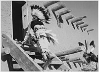 Dance, San Ildefonso Pueblo, New Mexico, dva domorodci kmene Tewa v čelenkách stoupající po schodech do domu, 1941
