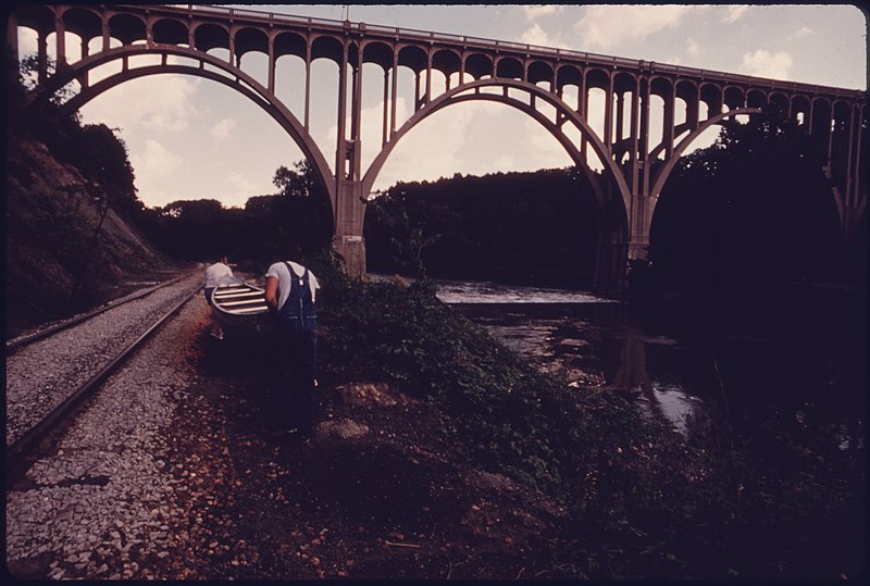 File:CANOEISTS ON THEIR WAY TO LAUNCH THEIR BOAT BELOW THE SPILLWAY AT THE BASE OF OHIO HIGHWAY 82 BRIDGE NEAR CLEVELAND.... - NARA - 557970.jpg