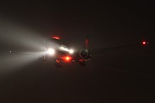 Boeing 777 with landing lights, navigation lights, and anti-collision beacon lights turned on DAL B777 Landing RWY 9R (13205519803).jpg