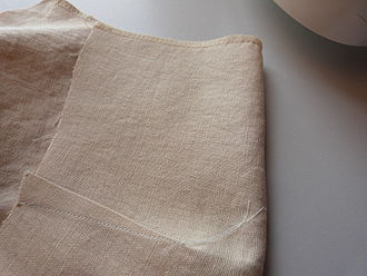 The reverse side of fabric showing where a dart has been taken in and stitched to tailor the shape of a garment to the wearer. Dart stitched.jpg