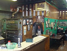 The interior of Di Fara Pizza, with DeMarco in the doorway