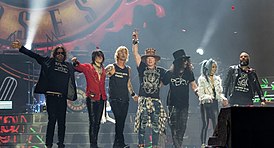 Guns N’ Roses на сцене Олимпийского стадиона в Лондоне 16 июня 2017 года. Слева направо: Диззи Рид, Ричард Фортус, Дафф Маккаган, Эксл Роуз, Слэш, Мелисса Риз, Фрэнк Феррер  (англ.) (рус.