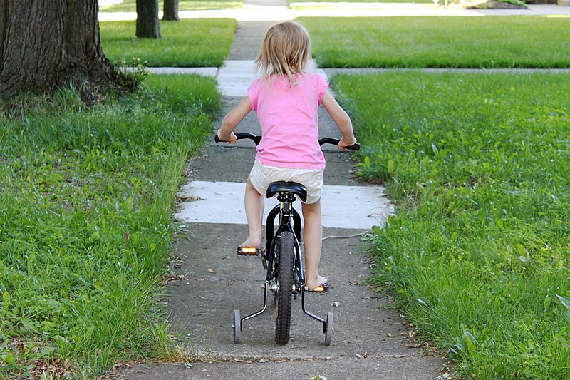 File:Girl on bike training wheels.jpg