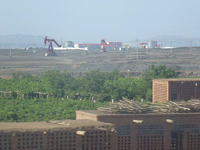Au premier plan : séchoirs à raisins et leurs vignes. Arrière-plan : exploitation du pétrole. Entre Liuyuan et Turfan. 2012.