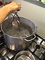 Lowering filled jam jars into boiling water bath canner.jpg
