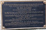 A history plaque, mounted on the Burd Street side of the bank building located on South Broadway & Burd Street in Nyack. The inscription says "Nay-ACK, which being translated means THE FISHING PLACE...The First Settlement ...Rockland County, NY...took place in 1675."