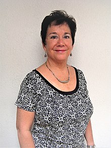 Photo de trois quarts d'une femme vêtue d'un t-shirt à col rond noir et blanc à imprimé floral portant des boucles d'oreilles en argent et un collier en argent.