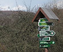 Wegweiser im Dorf. Fernsehturm im Hintergrund