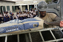 ABD Donanması 050310-N-0411D-012 Builder İnşaatçı Will Robinson, Naval Mobile Construction Battalion One'a (NMCB-1) atandı, bir torba çimentoyu Gonaives, Haiti'de bir çimento karıştırıcısına boşaltmaya hazırlanıyor.jpg