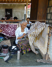 زنان صنعتگر باتیک در جاوه که با استفاده از قلم کلاقه و موم در یک تابهٔ کوچک گرم شده، الگوهای پیچیده می‌کشند