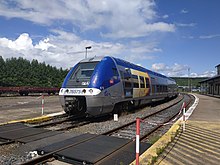 Piattaforma di una stazione con un treno TER parcheggiato a fianco.