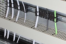 Strain relief plate inside an electrical enclosure, mounted on a 35 mm DIN rail shape H Zugentlastungsleiste Hutschiene Schaltschrank.jpg