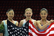 The ladies' medalists hold up the American flag. From left: Mirai Nagasu (3rd), Rachael Flatt (1st), Caroline Zhang (2nd). 2008 WJC Ladies Podium.jpg