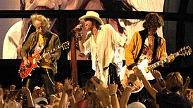 Брэд Уітфард, Стывен Тайлер і Джо Пэры з «Aerosmith» выступаюць на «NFL Kickoff» у Вашынгтоне, акруга Калумбія, 4 верасня 2003 года.