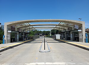 A bus station with an arched canopy over the platforms and bus lanes