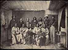 Conference at Fort Weld on September 28, 1864. Some of the identifications of Natives are uncertain. Front row, kneeling, left to right: Major Edward W. Wynkoop, commander at Fort Lyon and later agent for the Cheyennes and Arapahoes; Captain Silas S. Soule, provost marshal, later murdered in Denver. Middle row, seated, left to right: White Antelope (or perhaps White Wolf), Bull Bear, Black Kettle, One Eye, Natame (Arapaho). Back row, standing, left to right: Colorado militiaman, unknown civilian, John H. Smith (interpreter), Heap of Buffalo (Arapaho), Neva (Arapaho), unknown civilian, sentry. Another identification states that Neva is seated on the left and the man next to Smith is White Wolf (Cheyenne). Another Identification for back row starring 3rd from left: John Simpson Smith, Heap of Buffalo, Bosse, Dexter Colley, unidentified. Camp Weld Conference.jpg