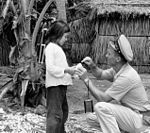 Chief Boatswain's Mate C. C. Gardner of the Coast Guard Cutter Point Mast gives a package of pencils, paper, candy, and plastic toys to a young Vietnamese girl during the cutter's civic action visit to Hon Nam Du Island. Coast Guard Squadron One Civic Actions.jpg